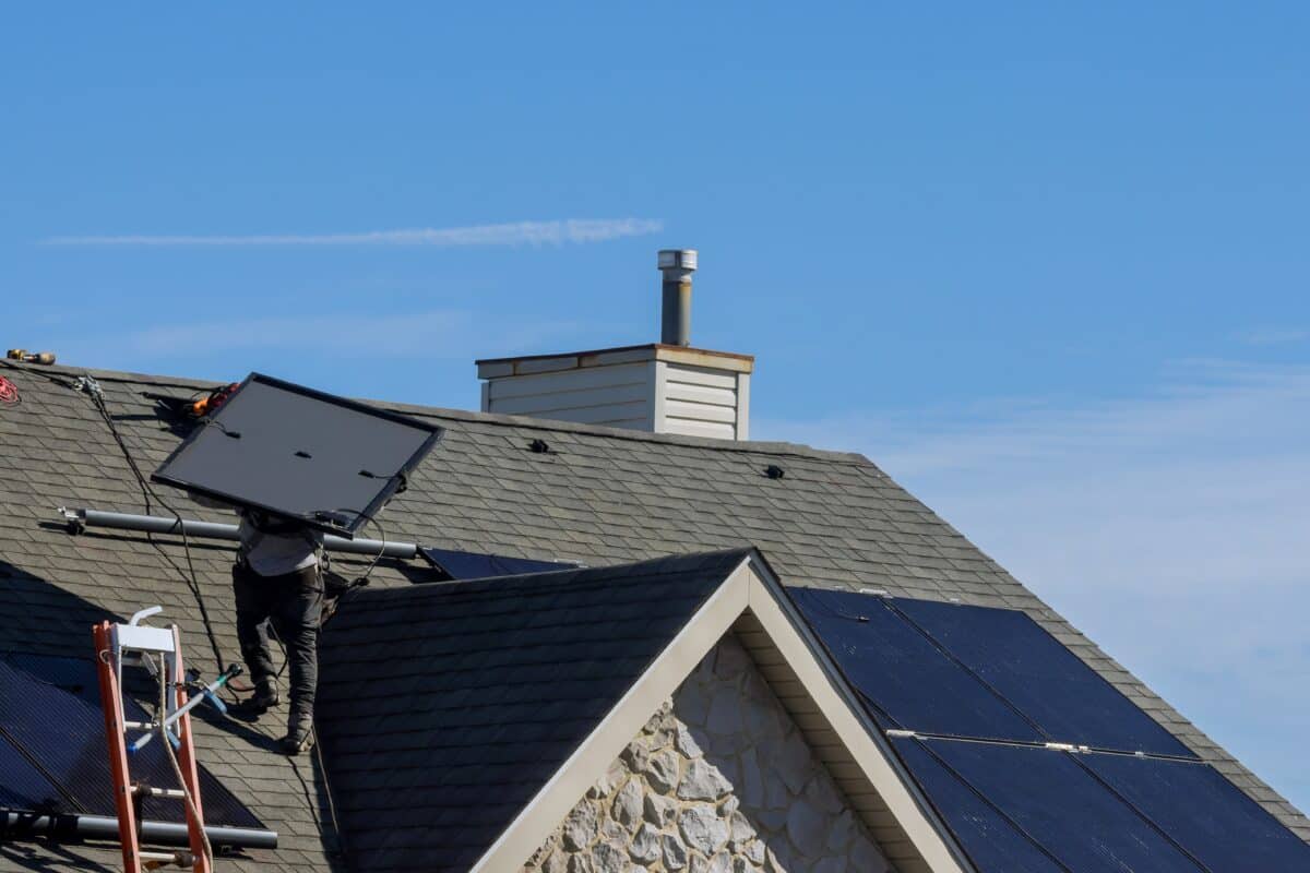 man installing photovoltaic solar panels alternative energy on roof