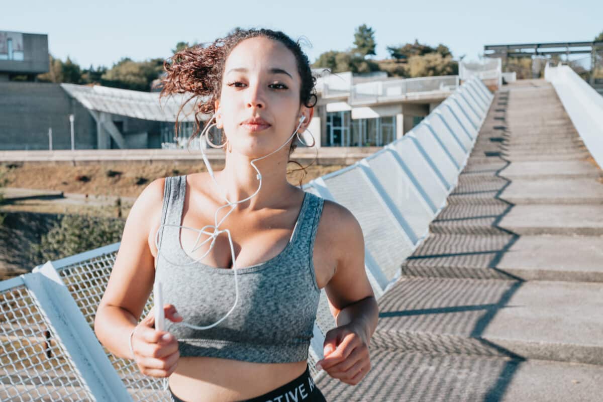 young woman running to lose weight after starting new habits and activities. copy space, woman listening music while training in an urban city place. leggins and top sport cloth, healthy life concept